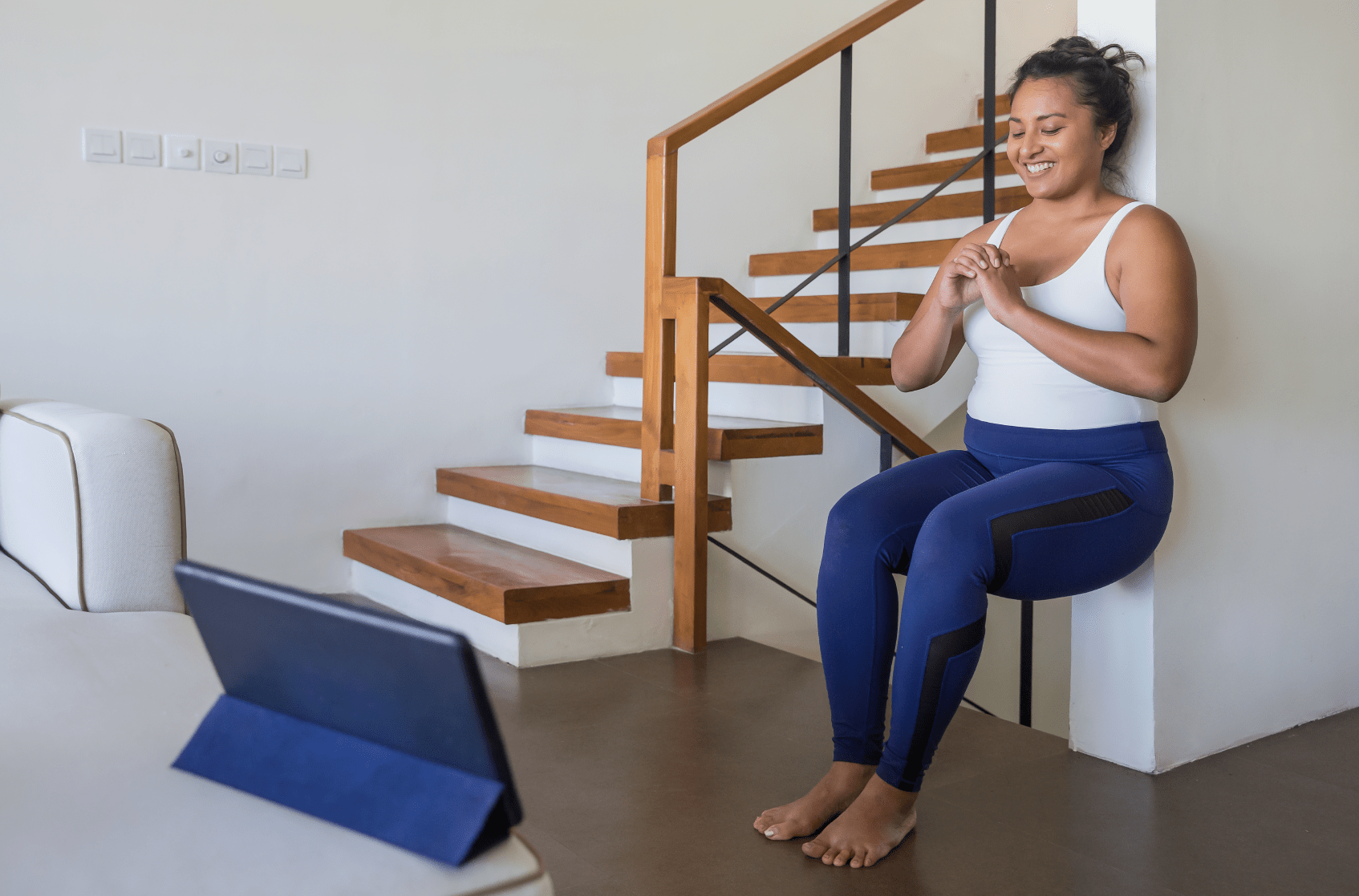 Woman doing an in-home workout, squatting against a wall.